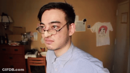 A Man Wearing Glasses And A Blue Shirt Has A T-Shirt On The Wall With A Picture Of A Woman On It GIF
