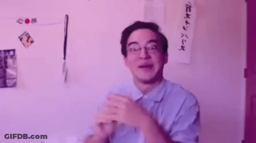 A Man Wearing Glasses And A Blue Shirt Is Clapping His Hands In Front Of A Purple Background . GIF