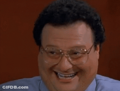 A Man Wearing Glasses And A Blue Shirt Is Laughing And Smiling . GIF