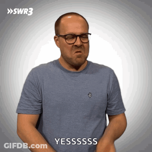 A Man Wearing Glasses And A Blue Shirt Is Making A Face And Says Yesssss GIF