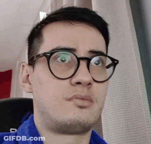 A Man Wearing Glasses And A Blue Shirt Is Making A Face GIF