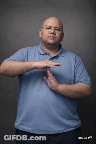 A Man Wearing Glasses And A Blue Shirt Is Making A Gesture With His Hand GIF