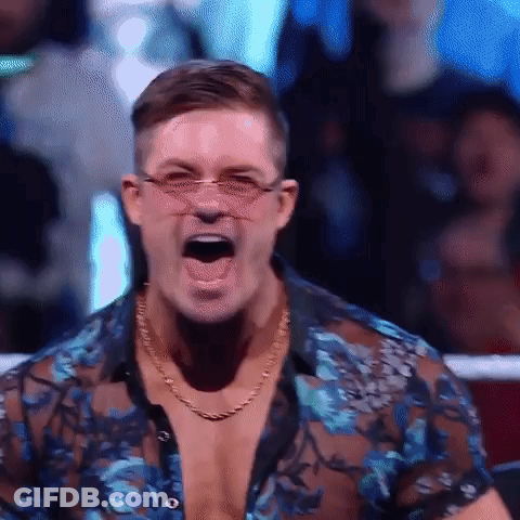 A Man Wearing Glasses And A Blue Shirt Is Screaming In A Ring . GIF