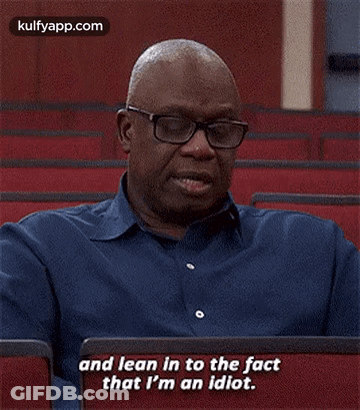 A Man Wearing Glasses And A Blue Shirt Is Sitting In A Lecture Hall . GIF