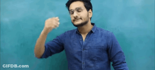 A Man Wearing Glasses And A Blue Shirt Is Standing In Front Of A Blue Wall And Making A Funny Face . GIF