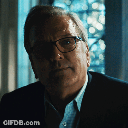 A Man Wearing Glasses And A Blue Shirt Looks At The Camera GIF