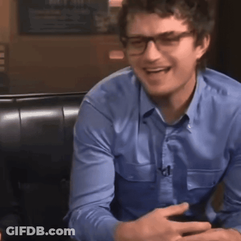 A Man Wearing Glasses And A Blue Shirt Smiles GIF