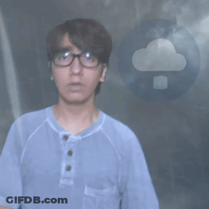 A Man Wearing Glasses And A Blue Shirt Stands In Front Of A Cloud GIF
