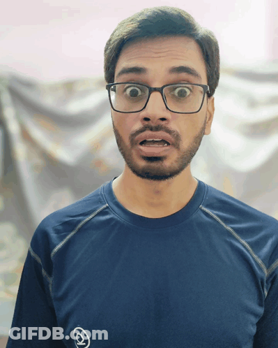A Man Wearing Glasses And A Blue Shirt With An O On It GIF