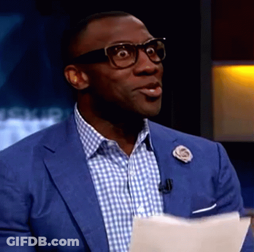 A Man Wearing Glasses And A Blue Suit Is Holding A Piece Of Paper In His Hand . GIF