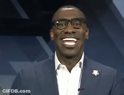 A Man Wearing Glasses And A Blue Suit Smiles GIF