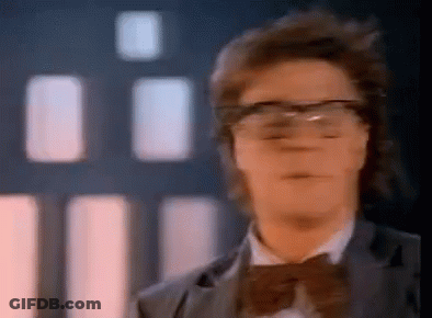A Man Wearing Glasses And A Bow Tie Looks At The Camera . GIF