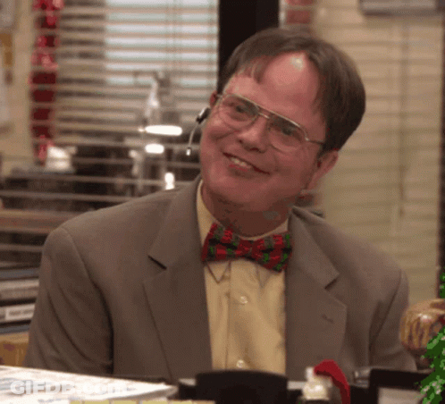 A Man Wearing Glasses And A Bow Tie Smiles At The Camera GIF