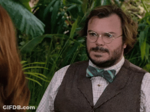 A Man Wearing Glasses And A Bow Tie Stands In The Jungle GIF