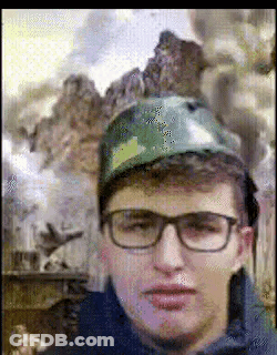 A Man Wearing Glasses And A Camouflage Hat Is Looking At The Camera GIF