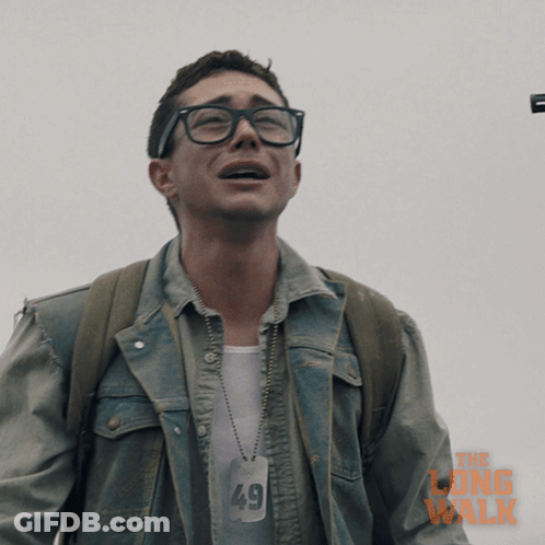 A Man Wearing Glasses And A Denim Jacket With The Long Walk Written On It GIF