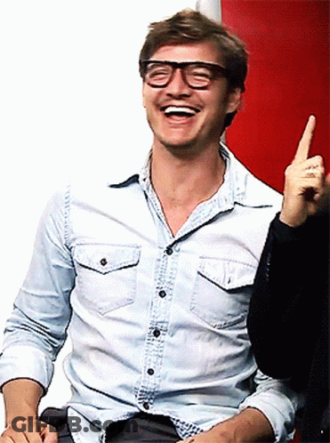 A Man Wearing Glasses And A Denim Shirt Is Laughing And Pointing Up GIF