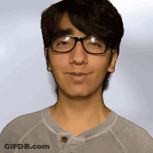 A Man Wearing Glasses And A Gray Shirt Is Smiling GIF