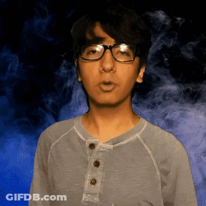 A Man Wearing Glasses And A Gray Shirt Is Standing In Front Of A Blue Background GIF