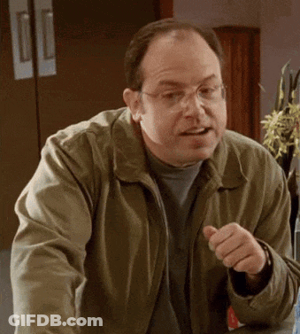 A Man Wearing Glasses And A Green Jacket Is Pointing At Something . GIF