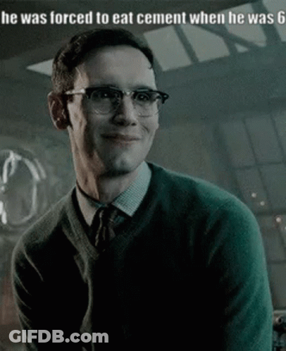 A Man Wearing Glasses And A Green Sweater Is Smiling And Looking At The Camera . GIF