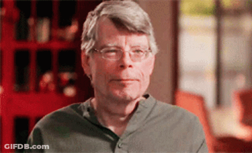 A Man Wearing Glasses And A Grey Shirt Is Looking At The Camera GIF