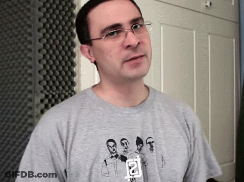 A Man Wearing Glasses And A Grey T-Shirt With A Picture Of A Group Of Men On It GIF