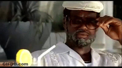 A Man Wearing Glasses And A Hat Is Holding His Glasses Up To His Face . GIF