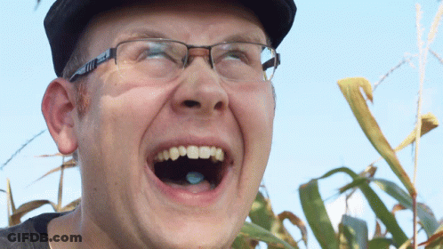 A Man Wearing Glasses And A Hat Is Laughing GIF