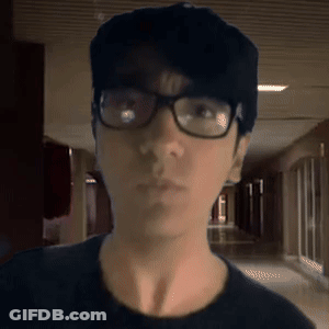 A Man Wearing Glasses And A Hat Is Looking At The Camera GIF