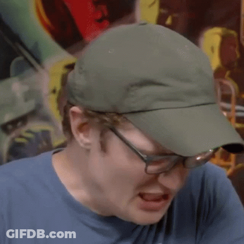 A Man Wearing Glasses And A Hat Is Making A Funny Face GIF