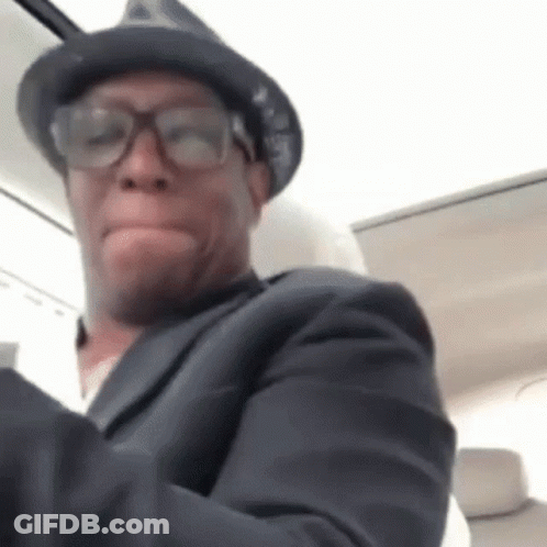 A Man Wearing Glasses And A Hat Is Making A Funny Face . GIF