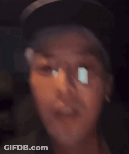 A Man Wearing Glasses And A Hat Looks At The Camera GIF