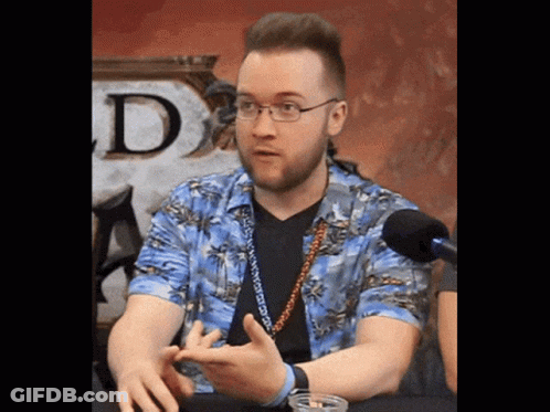 A Man Wearing Glasses And A Hawaiian Shirt Is Sitting In Front Of A Microphone GIF