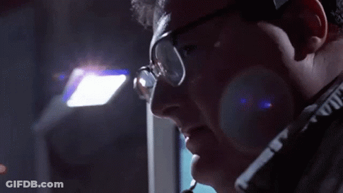 A Man Wearing Glasses And A Headset Is Looking Down GIF