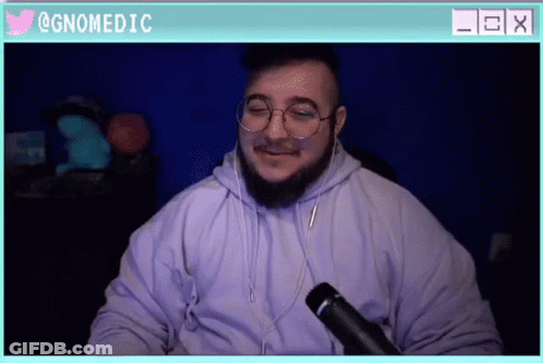 A Man Wearing Glasses And A Hoodie Is Sitting In Front Of A Microphone With A Twitter Icon Above Him GIF