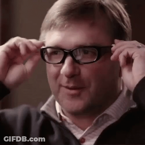A Man Wearing Glasses And A Jacket Is Adjusting His Glasses . GIF