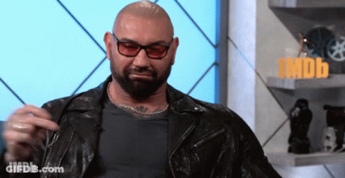 A Man Wearing Glasses And A Leather Jacket Is Standing In Front Of A Sign That Says Imdb On It GIF