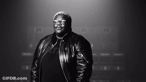 A Man Wearing Glasses And A Leather Jacket Smiles In A Black And White Photo GIF