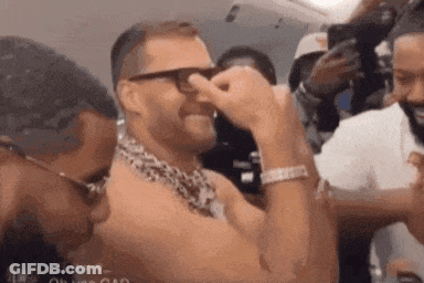 A Man Wearing Glasses And A Leopard Print Scarf Is Covering His Nose . GIF