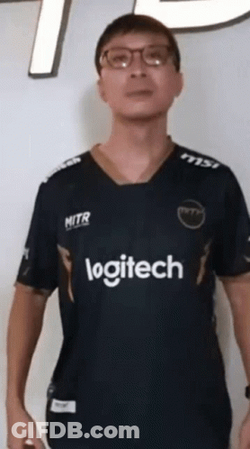 A Man Wearing Glasses And A Logitech Shirt Stands In Front Of A White Wall GIF