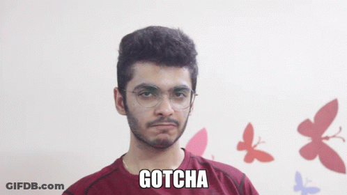 A Man Wearing Glasses And A Maroon Shirt With Gotcha Written On It GIF