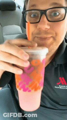 A Man Wearing Glasses And A Marriott Shirt Drinks A Pink Drink GIF