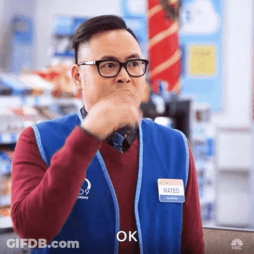 A Man Wearing Glasses And A Name Tag That Says Mateo Is Holding His Hand To His Mouth And Saying Ok . GIF