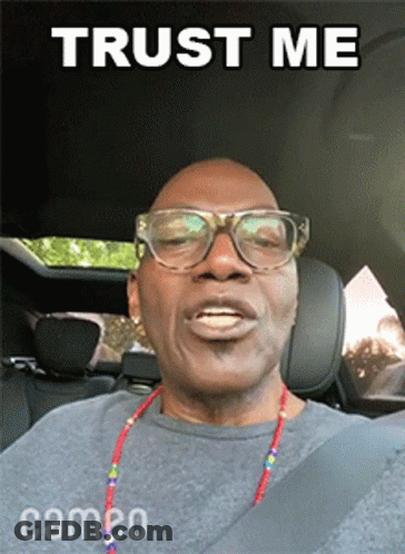 A Man Wearing Glasses And A Necklace Is Sitting In A Car With The Words Trust Me Above Him GIF