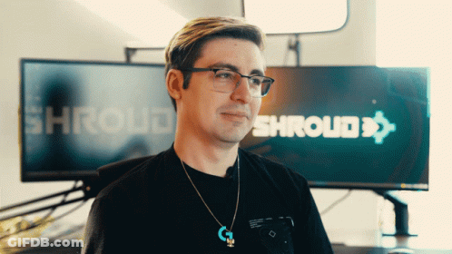 A Man Wearing Glasses And A Necklace Stands In Front Of A Screen That Says Shroud GIF