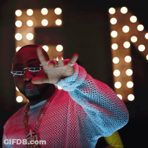 A Man Wearing Glasses And A Necklace That Says Fendi Is Making A Peace Sign GIF