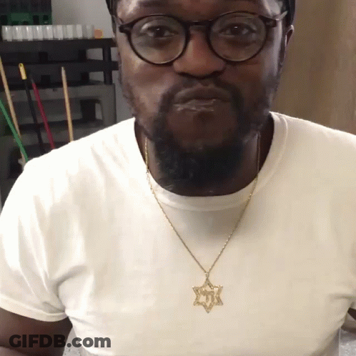 A Man Wearing Glasses And A Necklace With A Star Pendant GIF