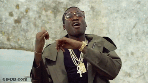 A Man Wearing Glasses And A Necklace With An Ankh Pendant GIF