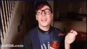 A Man Wearing Glasses And A Ny Yankees Shirt Is Holding A Bottle Of Ketchup In His Hand . GIF
